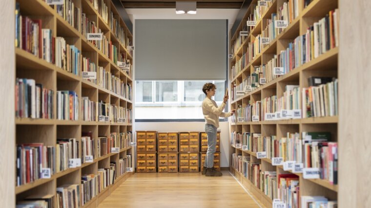 A young student looking for a book in a library